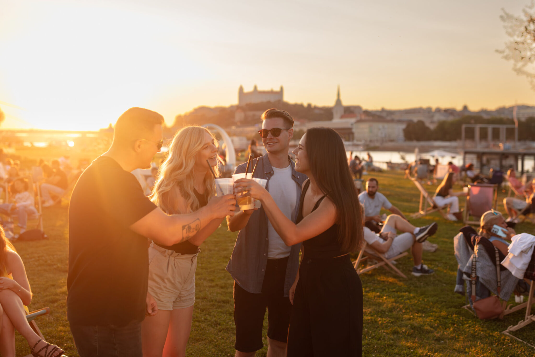 Tyrsak beach with people and drinks with Bratislava Castle.